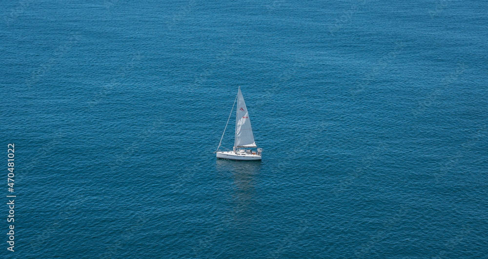 Top view of a sailboat in the peaceful blue ocean