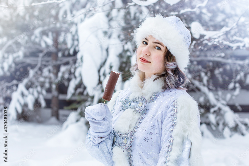 Girl in the costume of the Snow Maiden eats popsicle. Funny shot. Winter. Christmas character Snow Maiden. New Year. Girl in the costume of the Snow Maiden eats popsicle. Funny shot. Winter. Christmas character Snow Maiden. New Year.