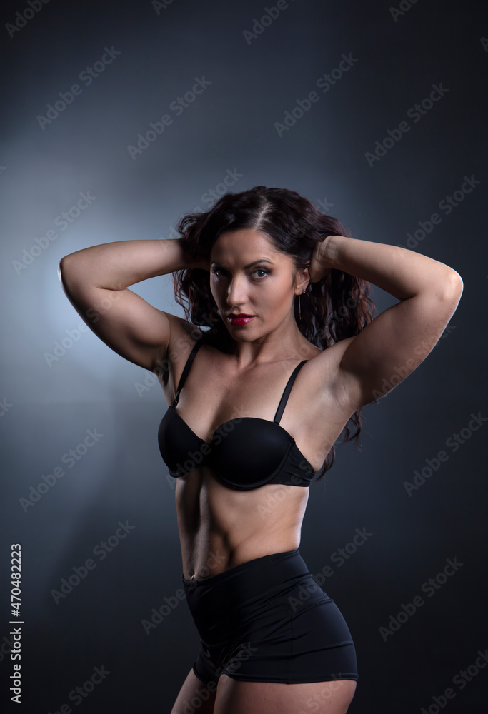Portrait of Strong fitness woman bodybuilder with black hair and tanned body.
