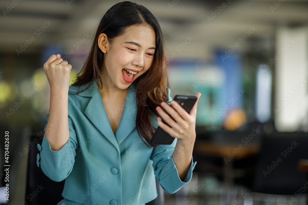 Excited happy woman looking at the phone screen, celebrating an online win, overjoyed young Asian female screaming with joy, isolated over a white blur background Excited happy woman looking at the phone screen, celebrating an online win, overjoyed young Asian female screaming with joy, isolated over a white blur background