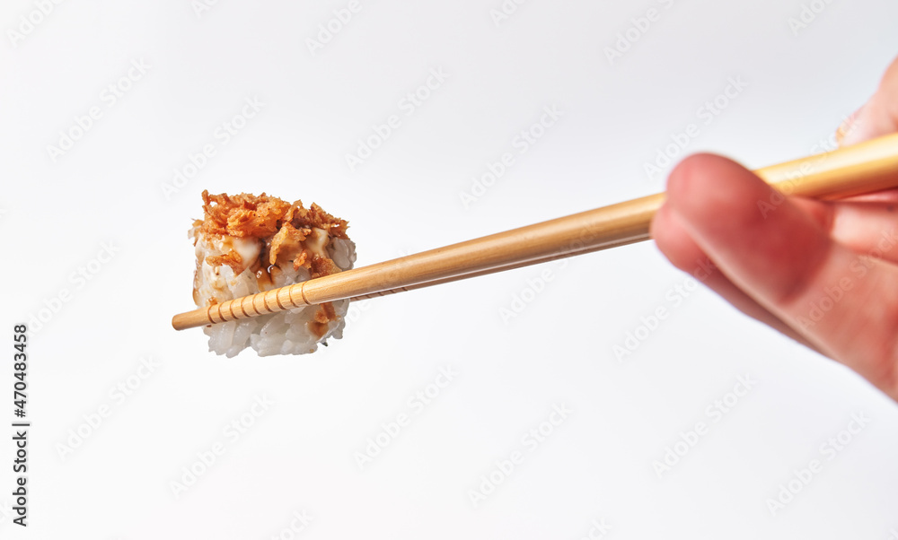 Chopsticks holding single uramaki sushi isolated on white background Chopsticks holding single uramaki sushi isolated on white background