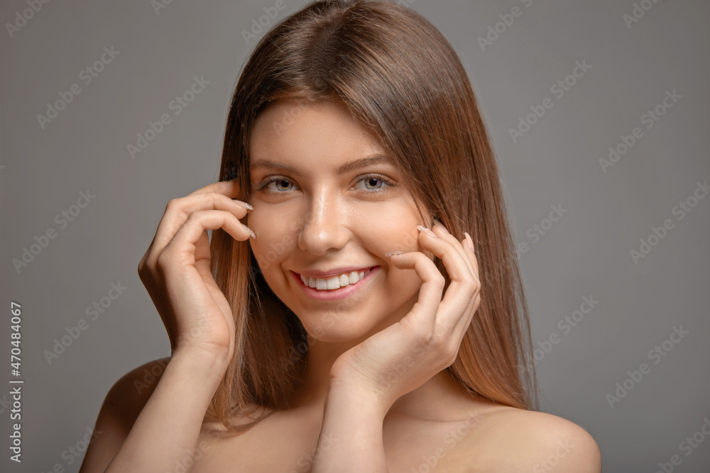 Young beautiful woman smiling on gray background Young beautiful woman smiling on gray background
