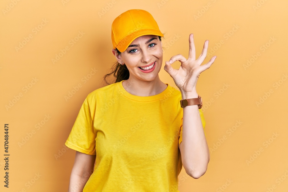 Young hispanic woman wearing delivery uniform and cap smiling positive doing ok sign with hand and fingers. successful expression. Young hispanic woman wearing delivery uniform and cap smiling positive doing ok sign with hand and fingers. successful expression.