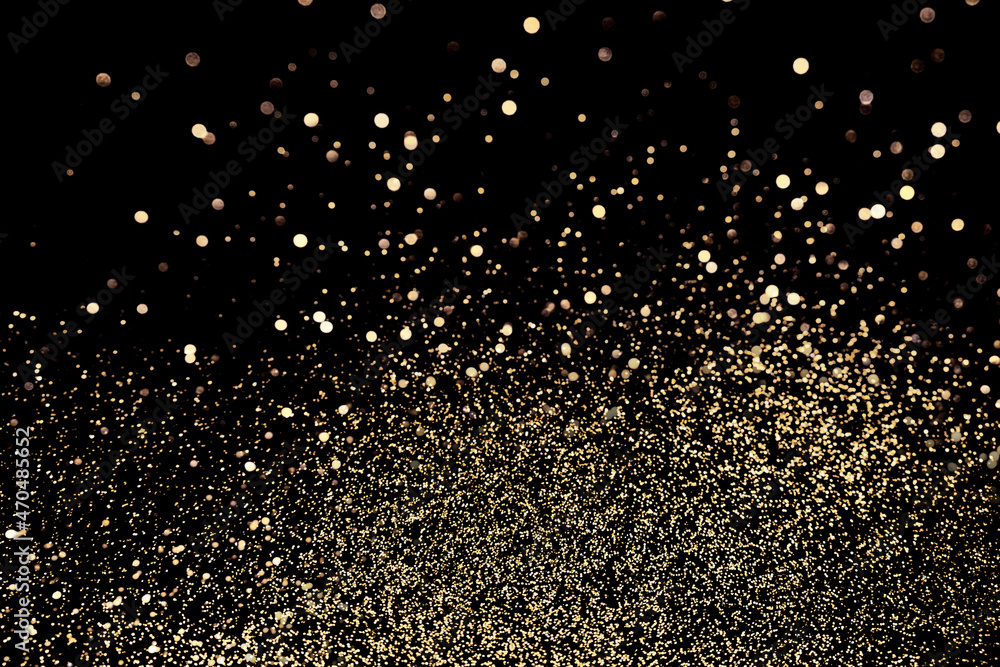 Black festive background. Abstract scattering of gold sparkles on black. Christmas backdrop, selective focus Black festive background. Abstract scattering of gold sparkles on black. Christmas backdrop, selective focus