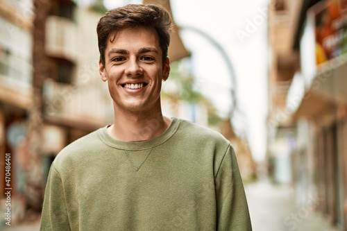 Young hispanic man smiling happy standing at the city.