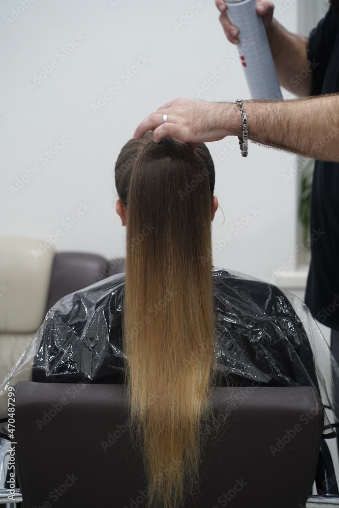 Naklejka premium Work in a hairdressing salon. High tail. Measurement with fingers by hairdresser before start.