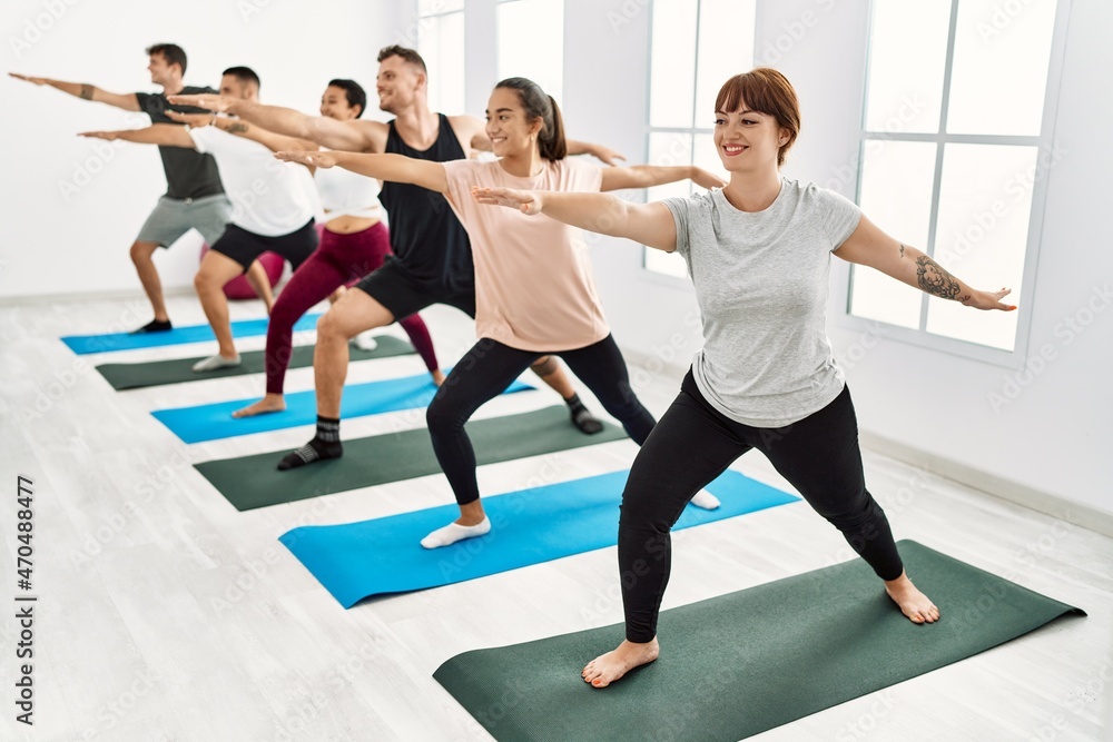 Naklejka premium Group of young hispanic people smiling happy training yoga at sport center.