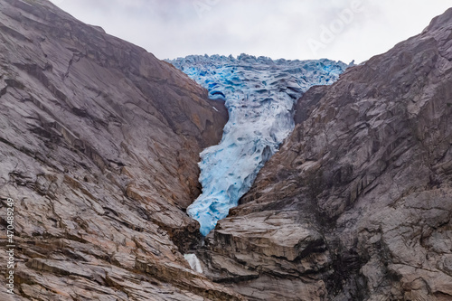 Scenic view on Briksdal glacier, and Norwegian mountains against cloudy dramatic sky