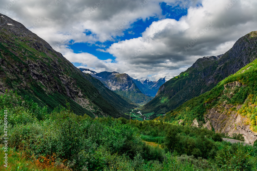 Scenic view from the road on a the valley between beautiful Norwegian mountains against dramatic cloudy sky Scenic view from the road on a the valley between beautiful Norwegian mountains against dramatic cloudy sky