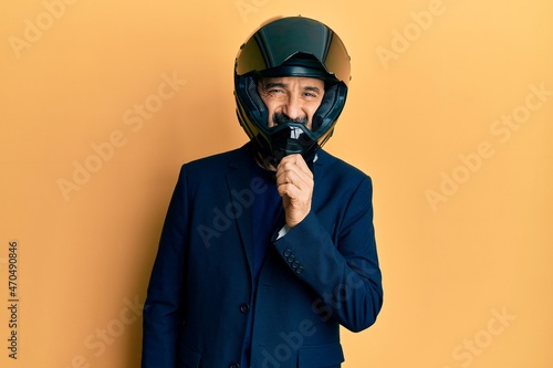 Middle age hispanic man wearing motorcycle helmet smiling looking confident at the camera with crossed arms and hand on chin. thinking positive.