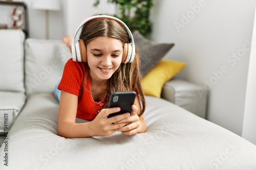 Adorable girl listening to music lying on sofa at home