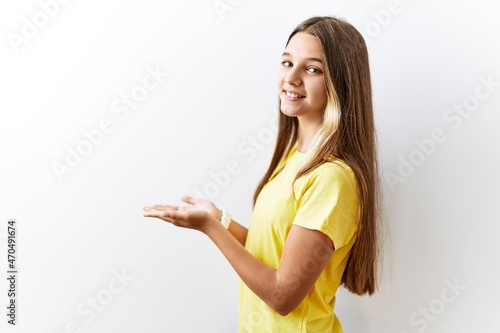 Young brunette teenager standing together over isolated background pointing aside with hands open palms showing copy space, presenting advertisement smiling excited happy