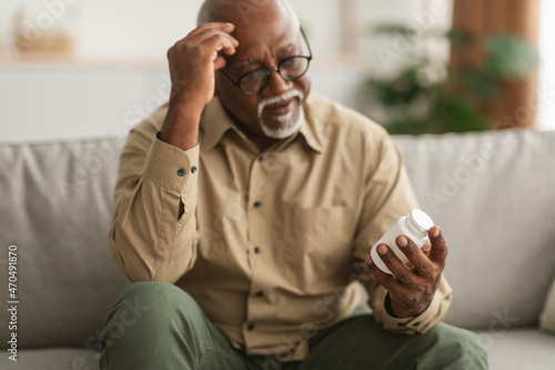 Senior African American Man Holding Medical Pills Reading Instruction Indoor photo