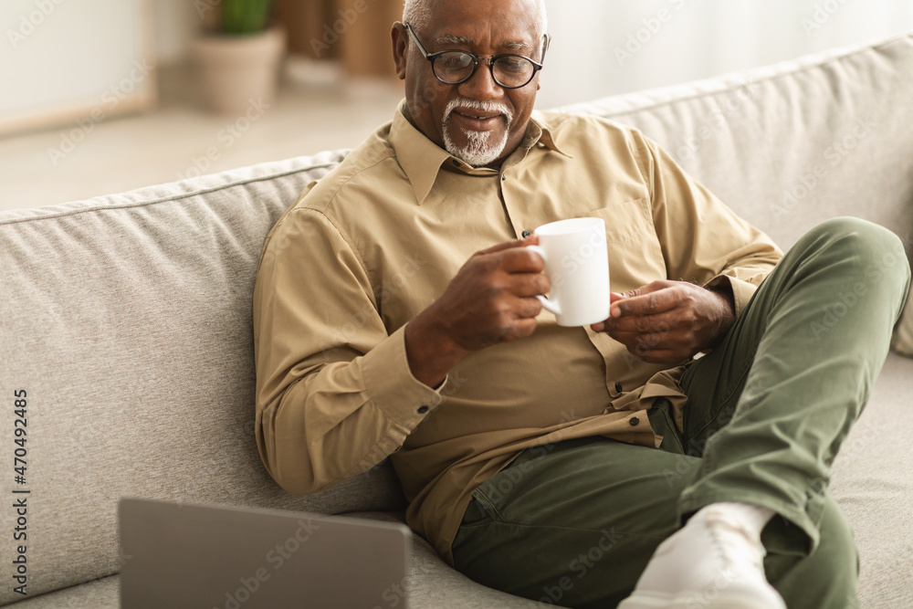 Senior Black Man Watching Movie On Laptop Drinking Coffee Indoor Senior Black Man Watching Movie On Laptop Drinking Coffee Indoor