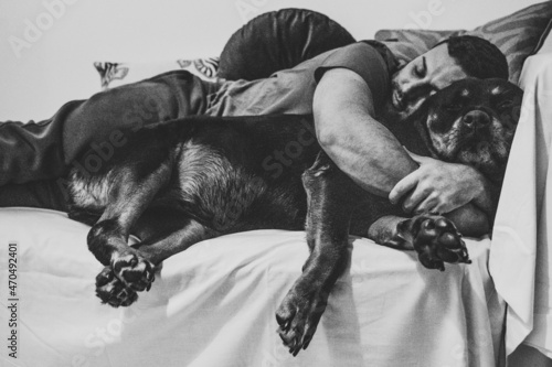 Hombre durmiendo con su perro rottweiler