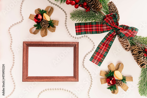 Fir branch with cones with a red-green bow, decorations and a frame for a photo or text on a light background
