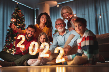 Family celebrating New Year, holding sparklers and illuminative numbers 2022