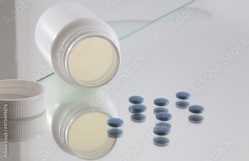 blue coated tablets in front of opened white plastic bottle