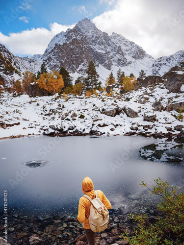 Hiker enjoying view at Orlenok Lake during autumn in North Caucasus, Arkhyz, Karachay-Cherkessia, Russia. concept of travel and active lifestyle