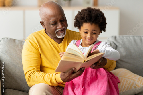 Photography Cheerful cute african american little granddaughter and senior grandpa reading b