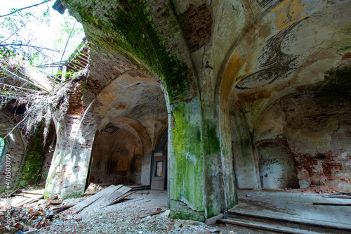 Columns of the vault of the hall of the old ruined abandoned Orthodox church in Russia. Broken floor and ceiling .Moss and peeling paint. Old red brick. Daylight.