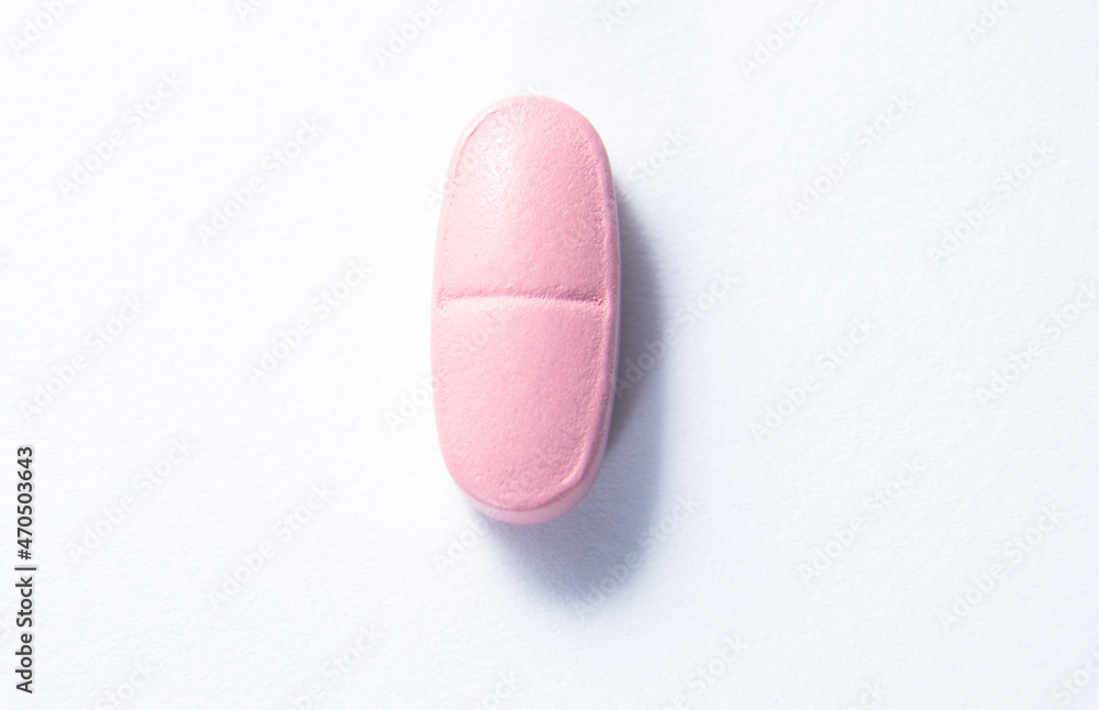 Pink pill on a white background close-up