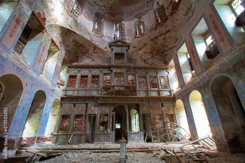 Horizontal photo of the destroyed iconostasis of an old destroyed and abandoned pro-Orthodox church in Russia. The walls of the church with peeling blue paint and old red bricks.