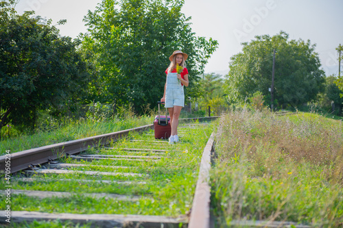 Traveler with flowers and suitcase on the railroad