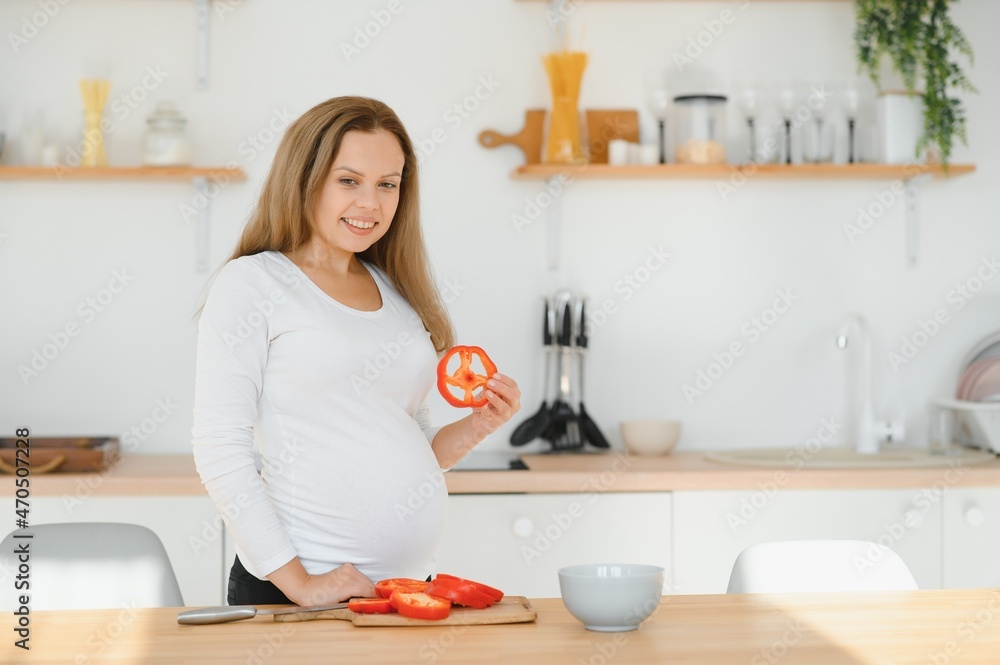 pregnant woman slicing vegetables at home in the kitchen