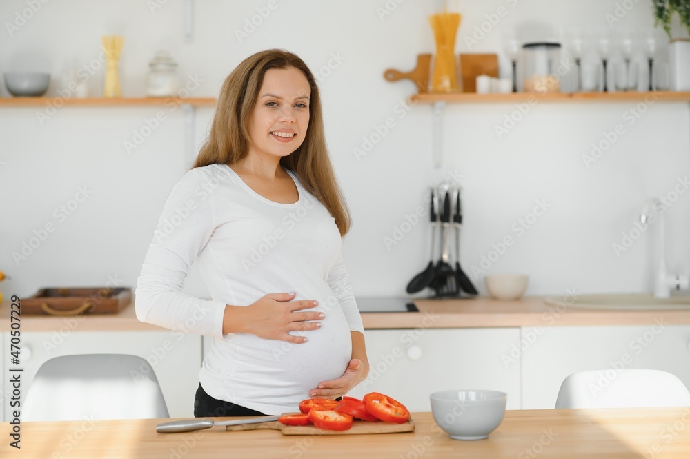 pregnant woman slicing vegetables at home in the kitchen pregnant woman slicing vegetables at home in the kitchen