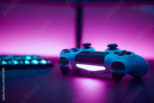 Low angle view game controller on table. Blank dual display and pink wall in background.
