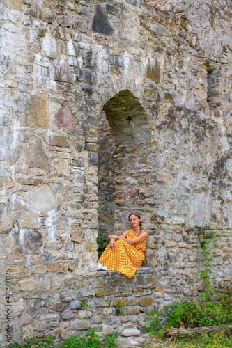 one woman in a yellow dress sits on the ruins of the wall