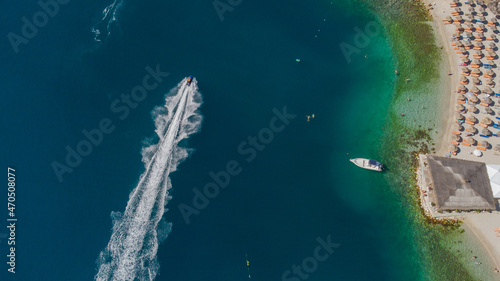 Aerial view of cruising motorboat and unknown anchored luxury motor yacht offshore in Dubai, UAE 
