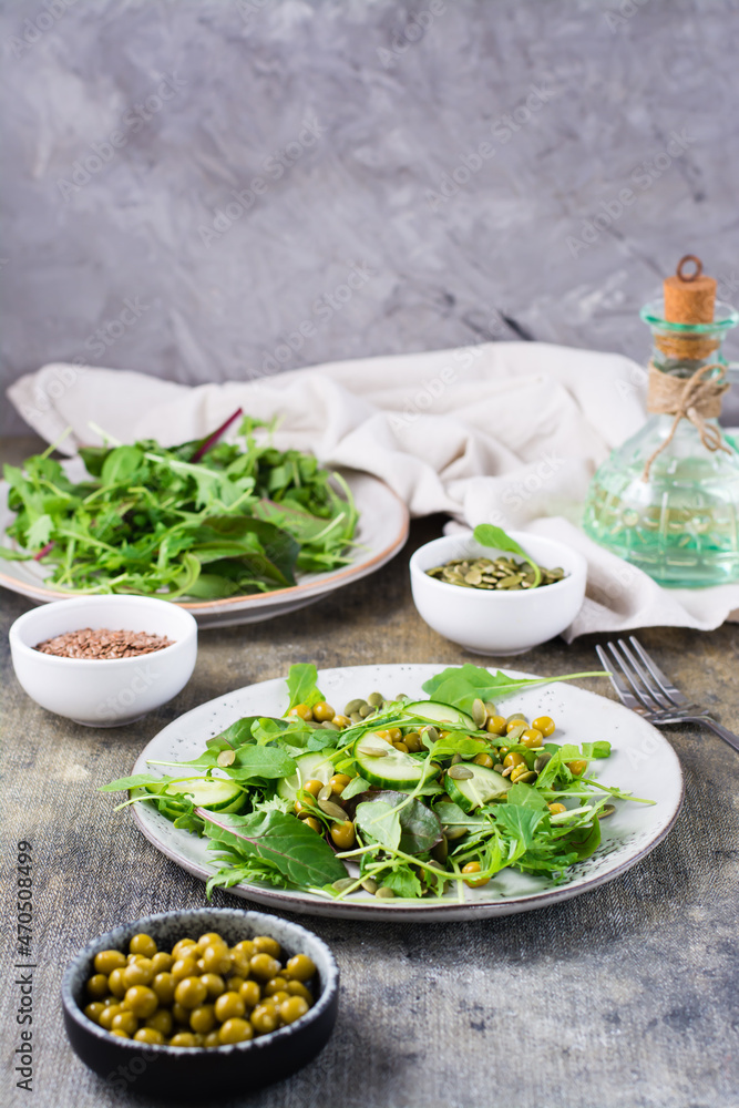 Vegetarian green salad with cucumber, peas and arugula, mizuna and chard leaves on a plate on the table. Vitamin and healthy food. Flexetarian diet. Vertical view Vegetarian green salad with cucumber, peas and arugula, mizuna and chard leaves on a plate on the table. Vitamin and healthy food. Flexetarian diet. Vertical view