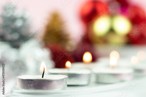 Tableau sur toile White Tealight Candles Illuminated In Row With Colorful Blur Bokeh Decorations On Light Pink Background
