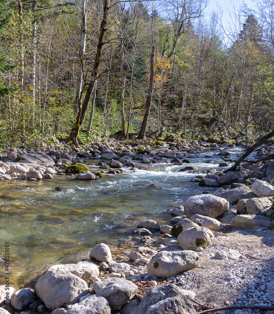 Autumn morning on a mountain river, a shallow riverbed with clear water and the rays of the sun illuminating the rocky bottom. Autumn morning on a mountain river, a shallow riverbed with clear water and the rays of the sun illuminating the rocky bottom.