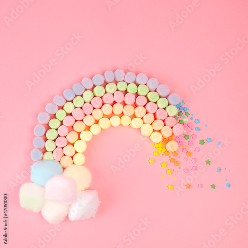 A square photo of a marshmallow rainbow candies design concept flat Layton a pastel pink background, Contemporary food art photo