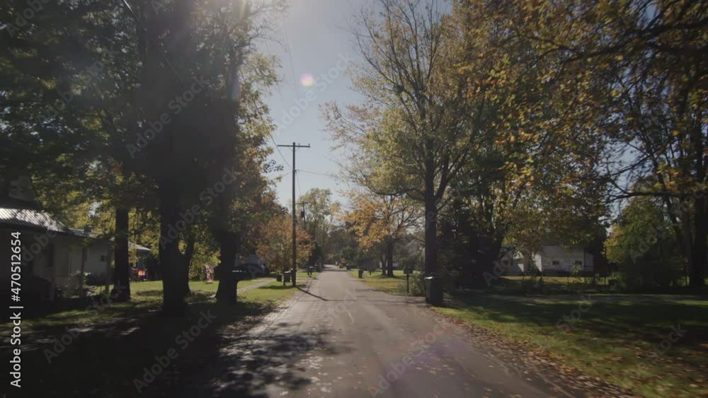 Drive along a typical street of an American town on a clear autumn day. The sun illuminates houses and trees beautifully. 4k shot Drive along a typical street of an American town on a clear autumn day. The sun illuminates houses and trees beautifully. 4k shot