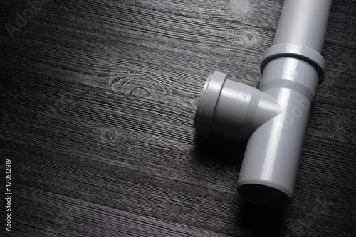 Drain plastic pipe on the black wooden workbench background.