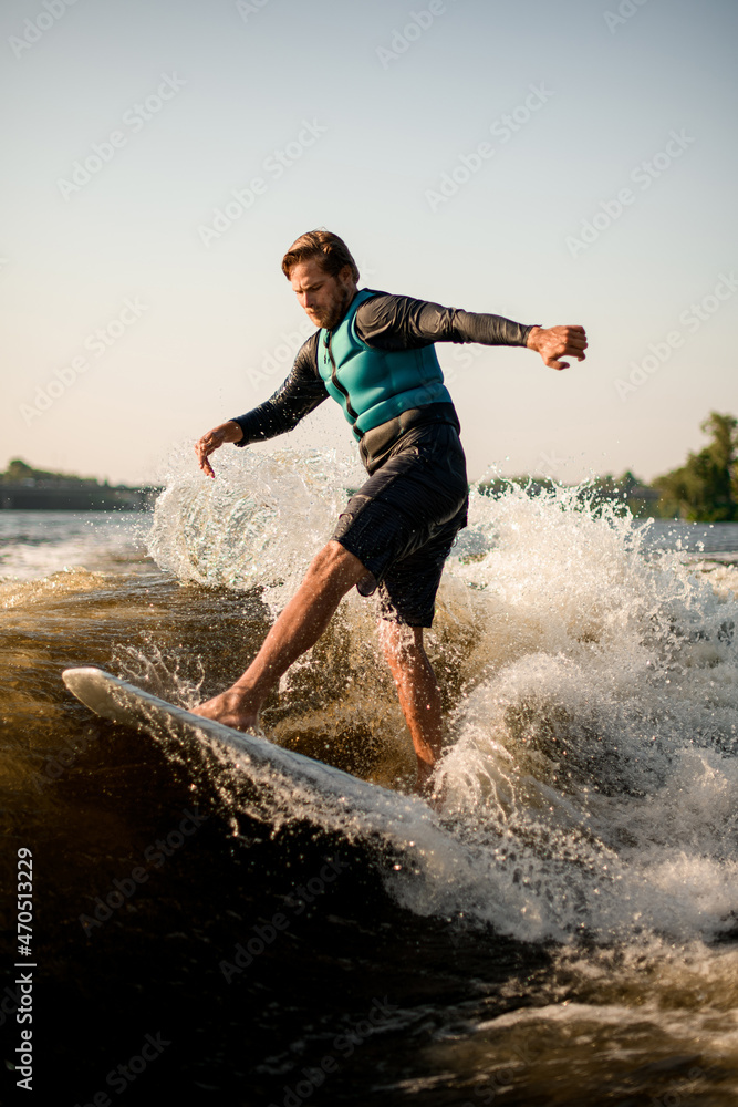 active man balancing on wave on wakesurf board.