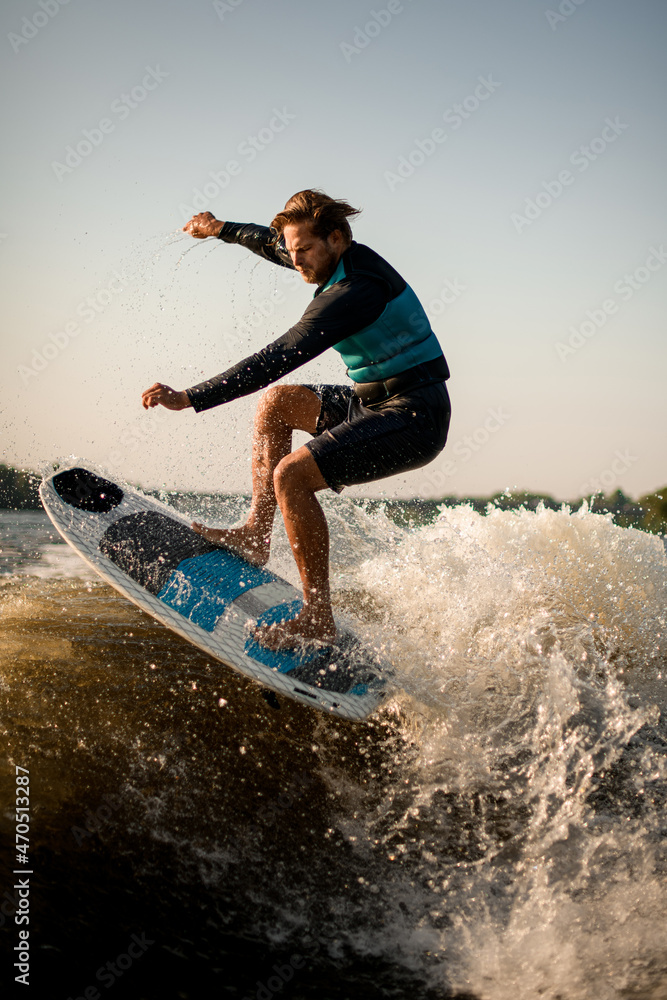 sports man skillfully makes jump with wakesurf board over the wave