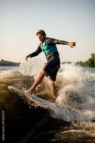 active man balancing on wave on wakesurf board.
