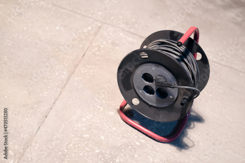 Electric power extension cord reel on the floor of construction site close up.