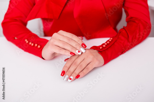 Beautiful female hands with stylish manicure nails, red gel polish, heart and Valentine's day design
