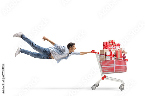 Foto Full length shot of a casual young man flying and holding a shopping cart with c