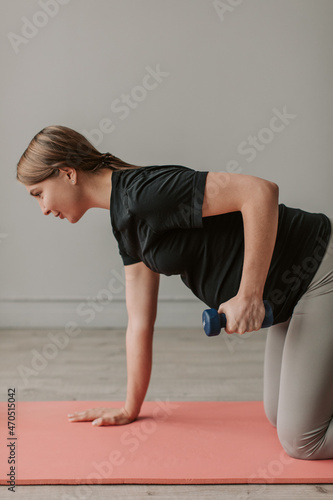 Happy young pregnant woman doing exercises at home in the living room.