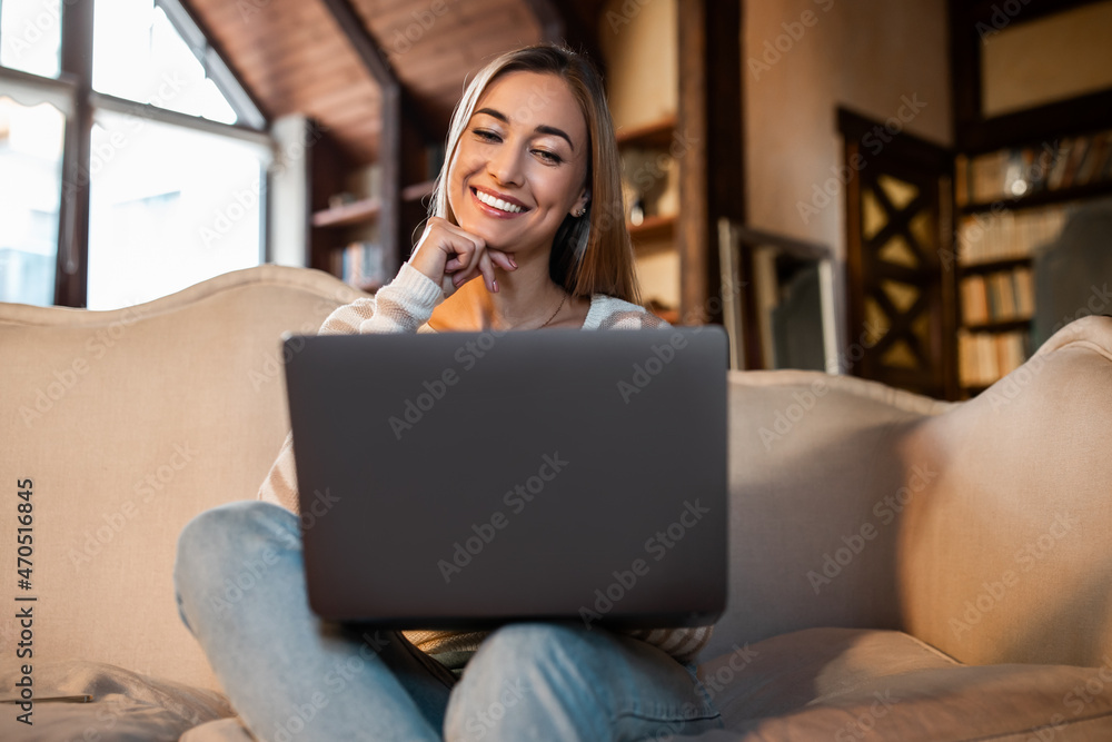 Naklejka premium Smiling woman working on laptop at home