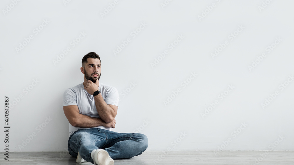 Sad shocked unhappy pensive handsome guy sit on floor, think and suffering from depression Sad shocked unhappy pensive handsome guy sit on floor, think and suffering from depression