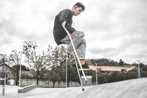 Guy on crutches performing stunt with skateboard