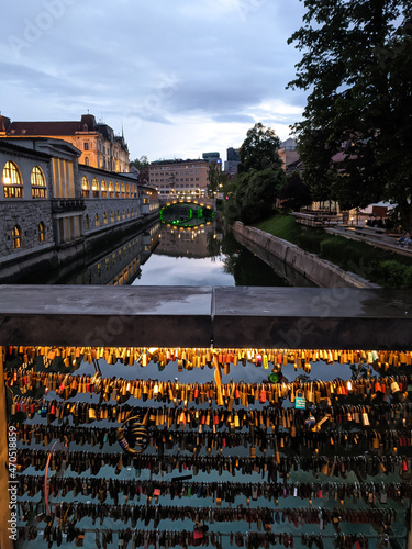 Ljubljana city center with river Ljubljanica flowing under bridge with love locks. Romantic night ambience by the river on the bridge over water